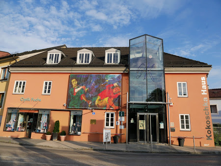 Das Bild zeigt die orange Fassade vom Kokoschka Museum Pöchlarn auf der ein vergrößertes Gemälde von Oskar Kokoschks angebracht ist..